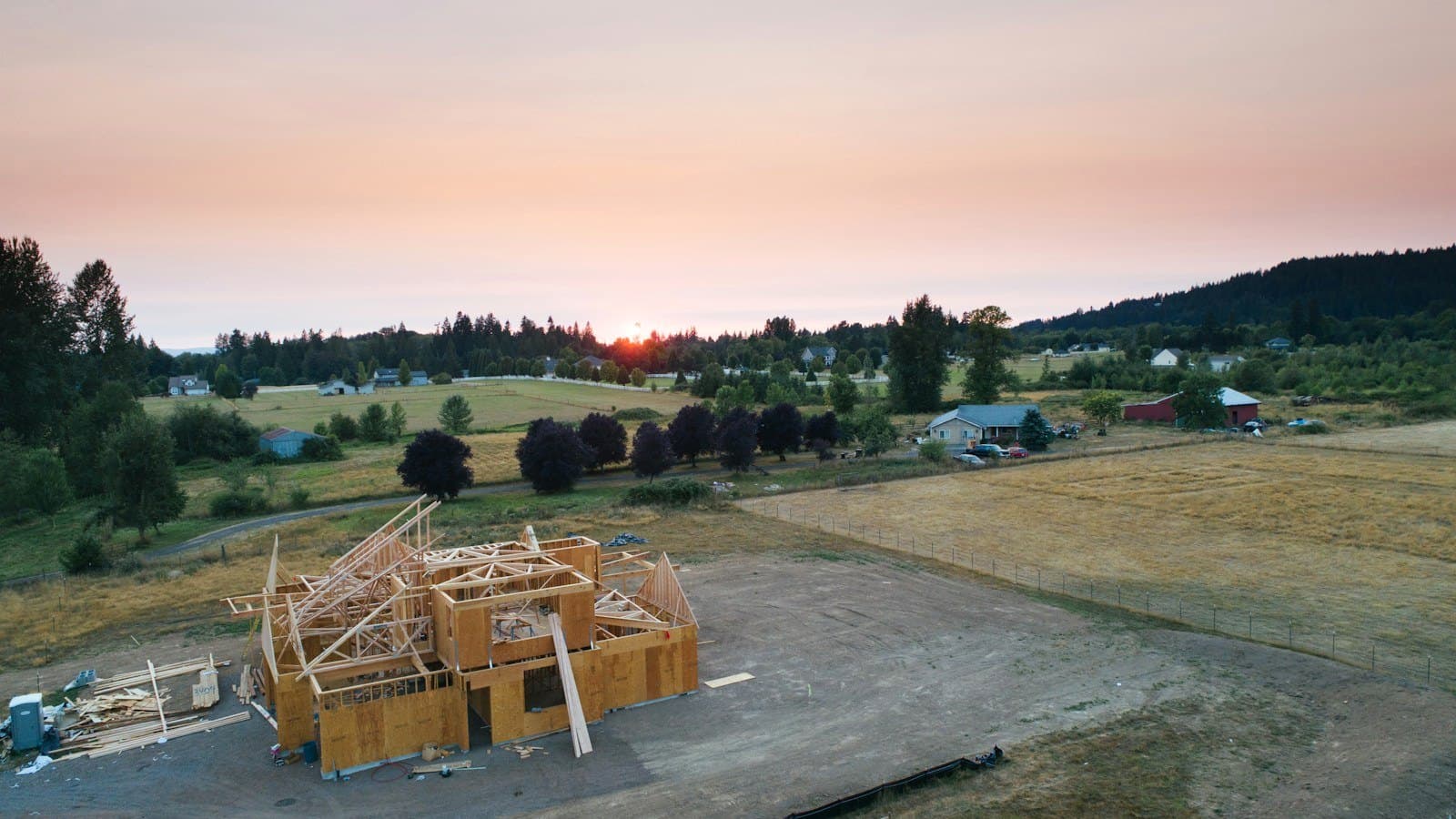 Aerial view of a wood-framed house under construction at sunset